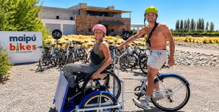 Pareja recorriendo la Ruta del Vino de Maipú en bicicleta adaptada frente a Bodega Tempus Alba